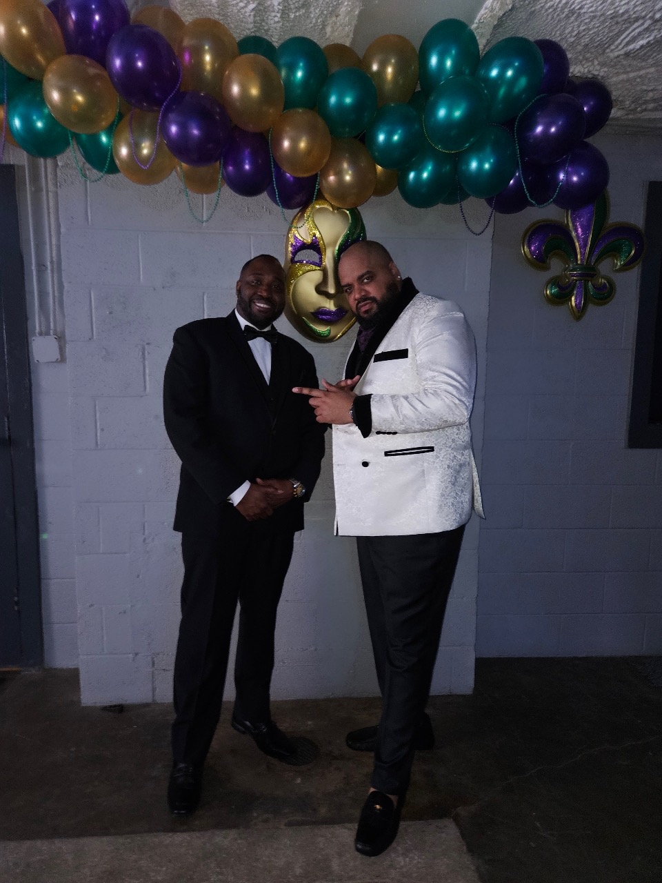 Hosts under the Mardi Gras balloon arch